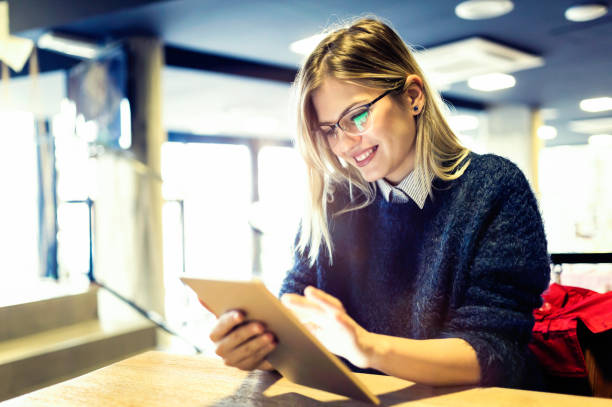 istock Happy young woman drinking coffee and using tablet 1058715762