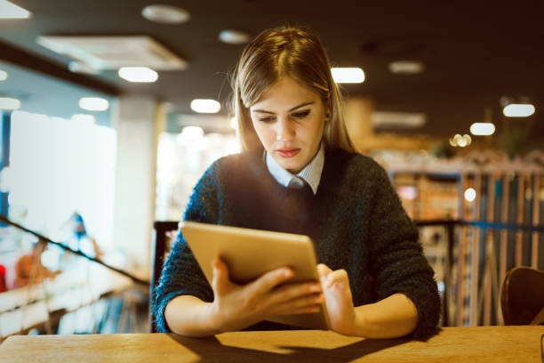 istock Happy young woman drinking coffee and using tablet 1058715764