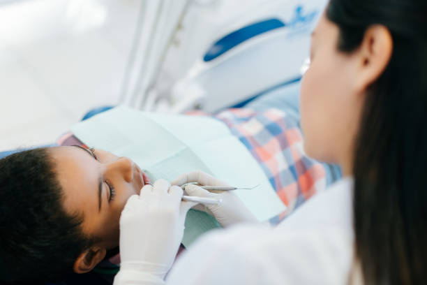 istock Female dentist checking girl's teeth 1058716468