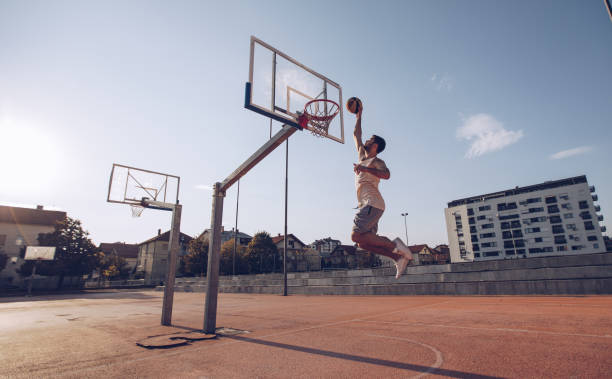 hombre joven saltando y haciendo un fantástico slam dunk - swish fotografías e imágenes de stock