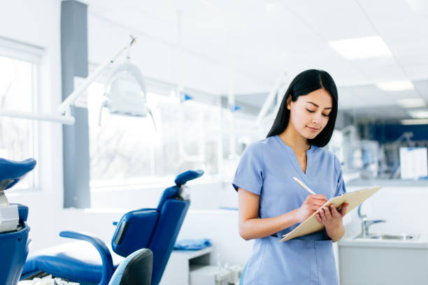 hermosa enfermera latina pie y escribir en el portapapeles - medical assistant fotografías e imágenes de stock