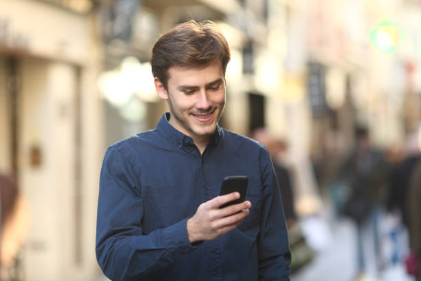 istock Smiley man checking smart phone content in the street 1058722560
