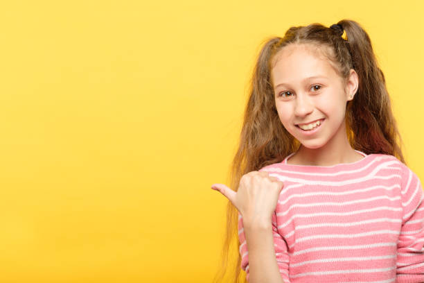 istock look left smiling girl point index finger empty 1058730534