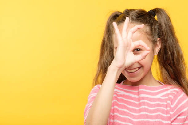 istock ok gesture smiling joyful girl look through finger 1058730718