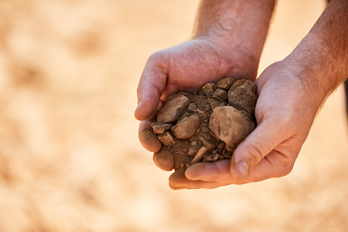 Closeup shot of a farmer holding soil and rocks in his hands