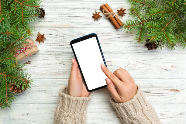 istock Christmas background: female hands messaging smartphone on rustic wooden table background with Christmas decoration. top view, flat lay 1058738240