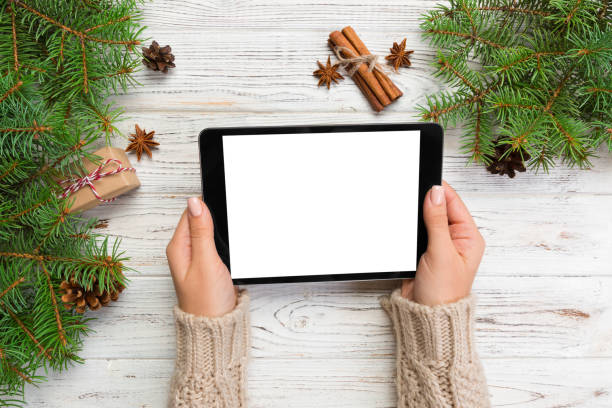 istock woman hands using tablet computer on wooden table bachground. cristmas shopping time. Happy Christmas mock up background, top view 1058738288