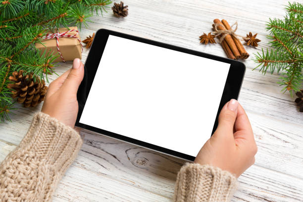 istock woman hands using tablet computer on wooden table bachground. cristmas shopping time. Happy Christmas mock up background, top view 1058738340