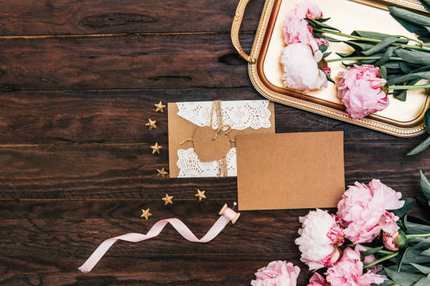 istock Mock up empty card with envelope and pink peony on vintage wooden background. Top view, copy space, wedding invitation concept 1058739512