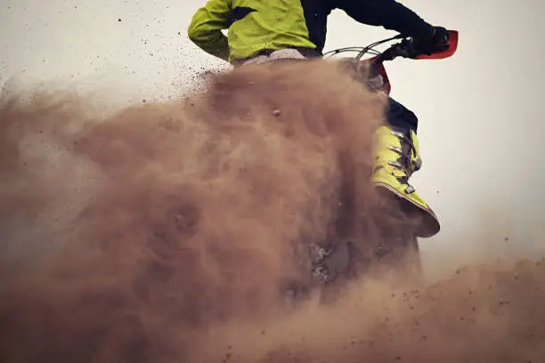 Motocross rider creates a huge cloud of dust and stone