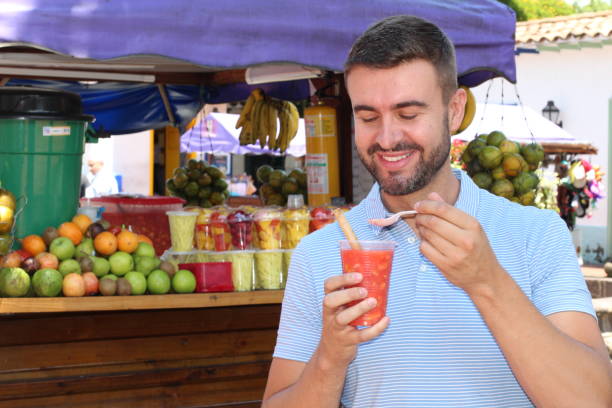 istock Man enjoying a fruit salad outdoors (salpicon) 1058749872