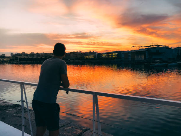 istock Man enjoying the sunset in a harbor 1058751166