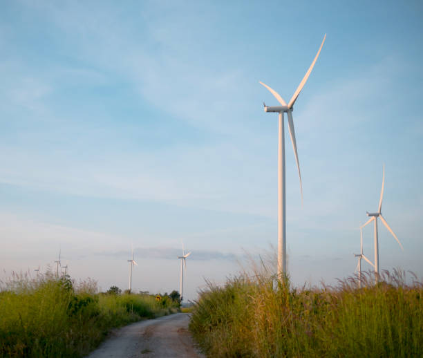 istock Wind turbine in grass field with Dirt road and blue sky 1058751602