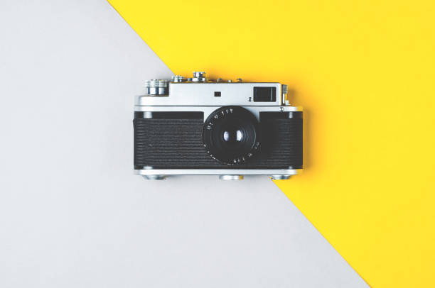 istock Old retro photo camera on grey-yellow background 1058752016