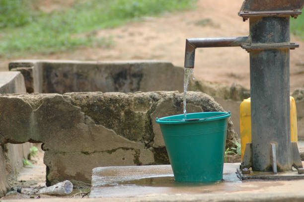 Bucket being filled at African well. stock photo