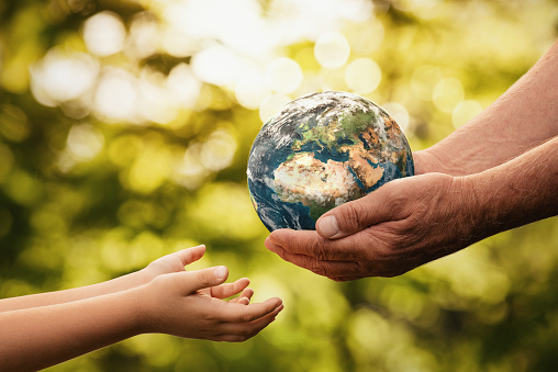 Manos mayores dando pequeño planeta tierra a un niño photo