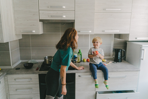 Young Caucasian woman on kitchen with little boy