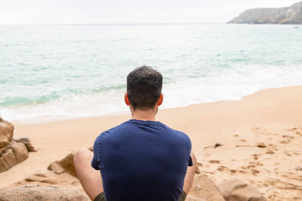 istock Man sat on rocks Relaxing at Pedn Vounder Beach 1058758954