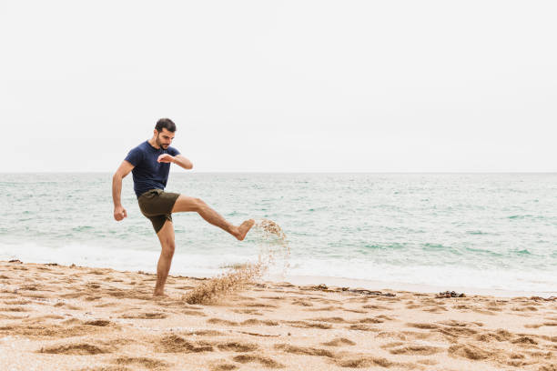 istock Man kicking sand at the beach 1058758956