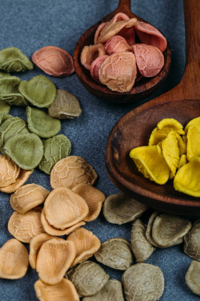 istock Traditional Italian Rainbow pasta. Colored raw pasta on a stone background 1058760094