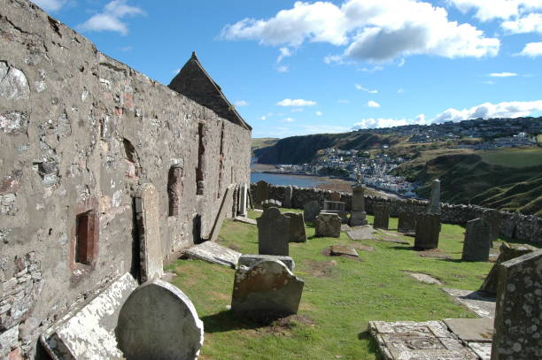 St John's church and kirkyard, Gardenstown, Scotland Aberdeenshire, Scotland: August 14th 2018 - Ancient ruined church of St John on clifftop above Gardenstown, Aberdeenshire, Scotland with the bay and village visible below. kirkyard stock pictures, royalty-free photos & images