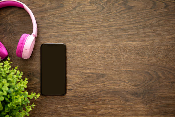 istock phone with black screen on wooden table with headphones 1058762410