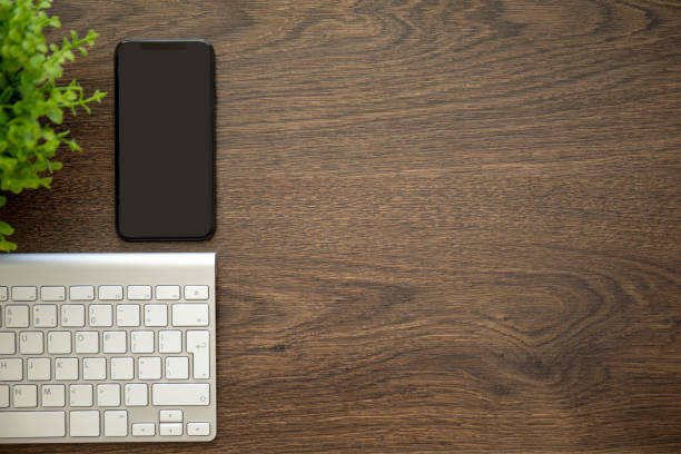 istock phone with black screen on wooden table with a keyboard 1058762414