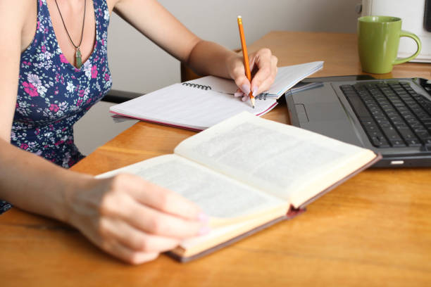 istock Girl sits at table and writes in notebook 1058767334