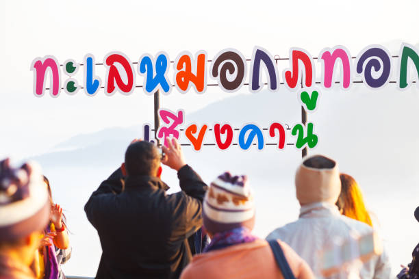 Tourists are standing near letters of lookout on Phu Tok mountain in north Thailand in province of Loie in sunrise.