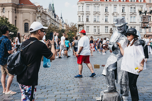 Prague, Czech Republic - August 23, 2018: Tourists taking photos with a living statue in Old Town Square, a historic square in the Old Town quarter of Prague.