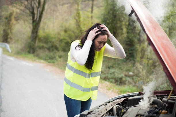 istock Smoke pours from young woman's car engine 1058777132