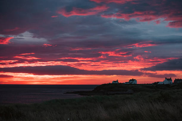 The sun rising over the beach, it is a fiery red colour.