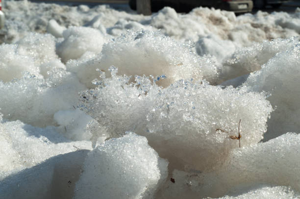 istock Texture, background, pattern. The spring snow melts. The beginning of a warm season, spring. Melting snow on the ground in the city with a mild morning sunlight. 1058782014