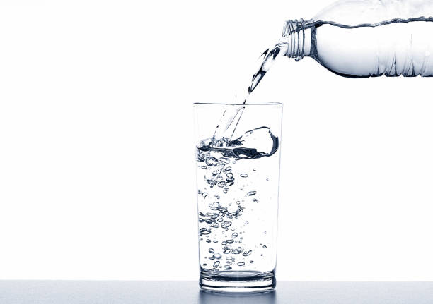 istock Pouring drinking water from bottle into glass on white background 1058793390