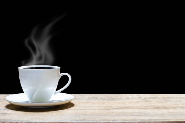 Hot cup of coffee on wooden table on dark background