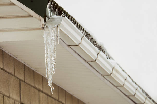 Roof cornice with overhang icy icicle gutter after thaw stock photo