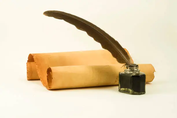 A two old parchment scrolls with a quill in a inkwell on a white background