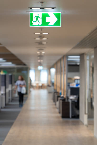 istock Green fire escape sign hang on the ceiling in the office. 1058803916