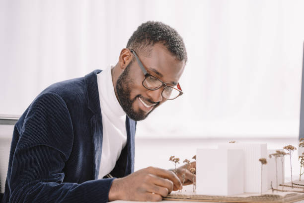 istock smiling bearded african american engineer working with business buildings model 1058804072