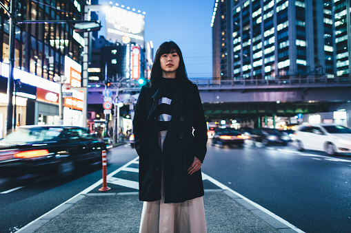 A young woman standing in the street at night in Tokyo.