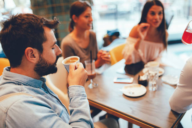 istock Young man enjoys coffee with friends in a cafe 1058812154