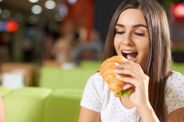 istock Hungry female biting croissant in cafe 1058812882