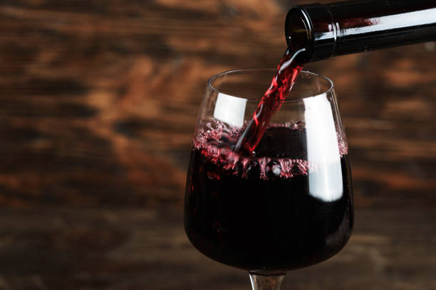 istock red wine pour into a glass on a wooden background 1058815344