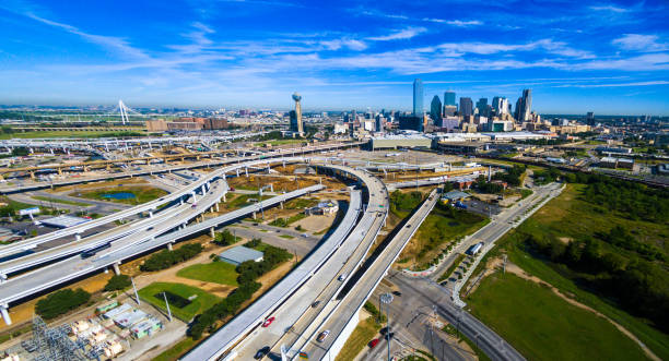 aerial drone view above sunny afternoon day time in Dallas , Texas above Intersecting curved Highway interchange leading towards Dallas Texas Downtown Skyline
