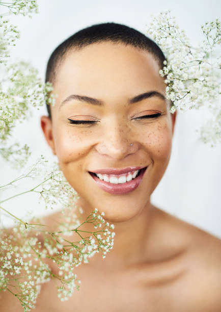 Be happy, be beautiful Studio shot of a beautiful young woman posing amongst delicate flowers shaved black women stock pictures, royalty-free photos & images