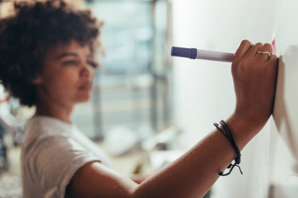 istock Woman writing important points on board at project meeting 1058825682