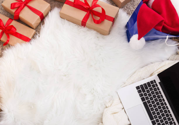 istock Christmas gift boxes, laptop and santa hat on white background 1058826328