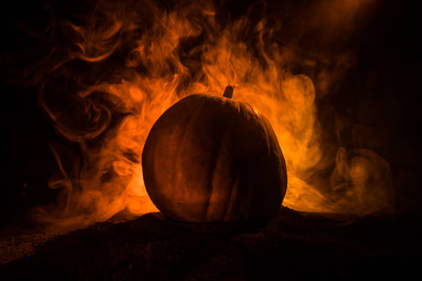 istock Halloween theme with pumpkin against smoky dark background. Empty space for text 1058826376
