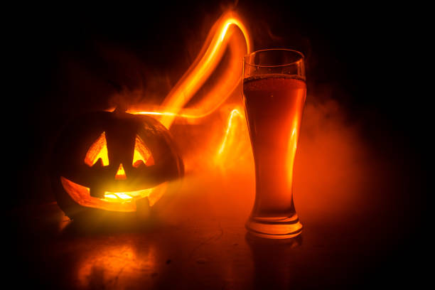 ハロウィーンのため木材の背景にカボチャの冷たい光のビールのグラス。新鮮なビールと暗いトーンの霧の背景にカボチャのガラス - glass autumn halloween food ストックフォトと画像