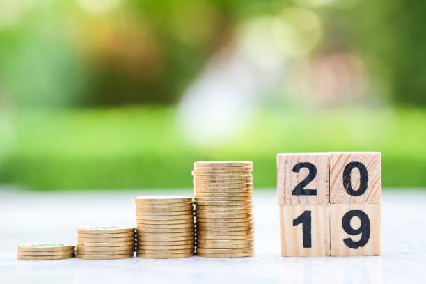 istock Step of coins stack and wooden blocks number 2019 on blur background. 1058826874